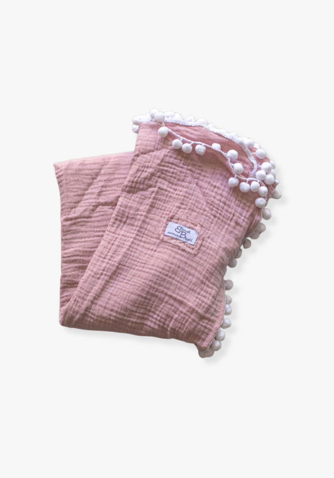 Dusty pink organic cotton baby blanket with soft white pom-pom trim, neatly folded with a visible Bondi Booti label, placed on a neutral background.