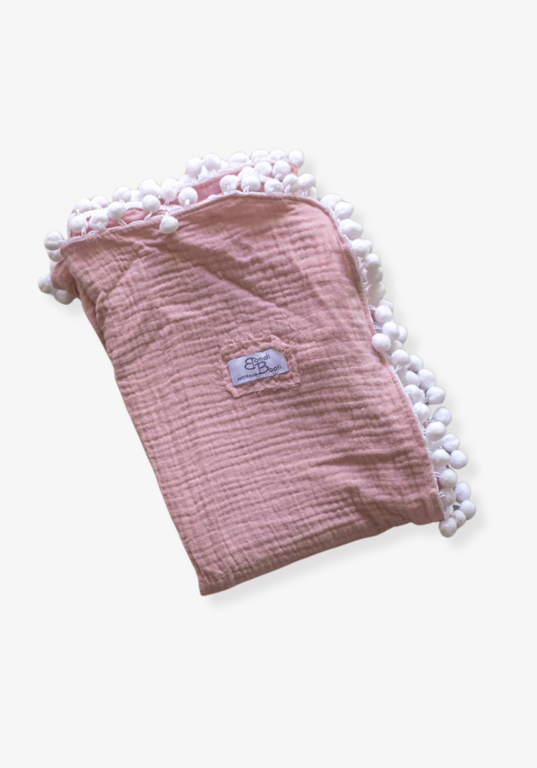 Dusty pink organic cotton baby blanket with soft white pom-pom trim, neatly folded with a visible Bondi Booti label, placed on a neutral background.