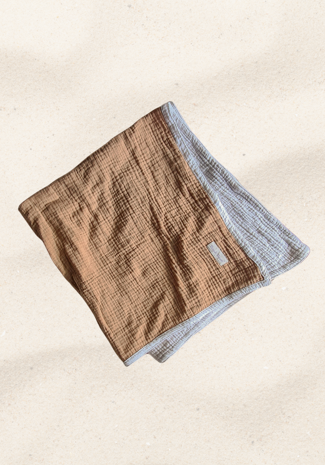 Reversible baby blanket in warm brown and white organic cotton, with visible Bondi Booti and “Made in Australia” labels, displayed on a neutral fabric background.