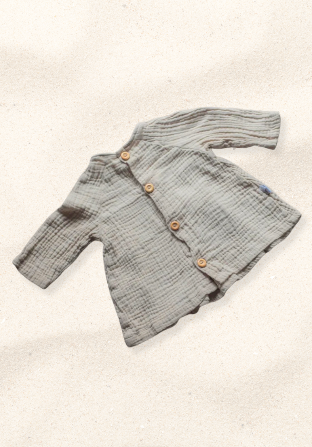 Boho-style baby dress in beige with embroidered hem, made from breathable cotton and displayed on a sand background