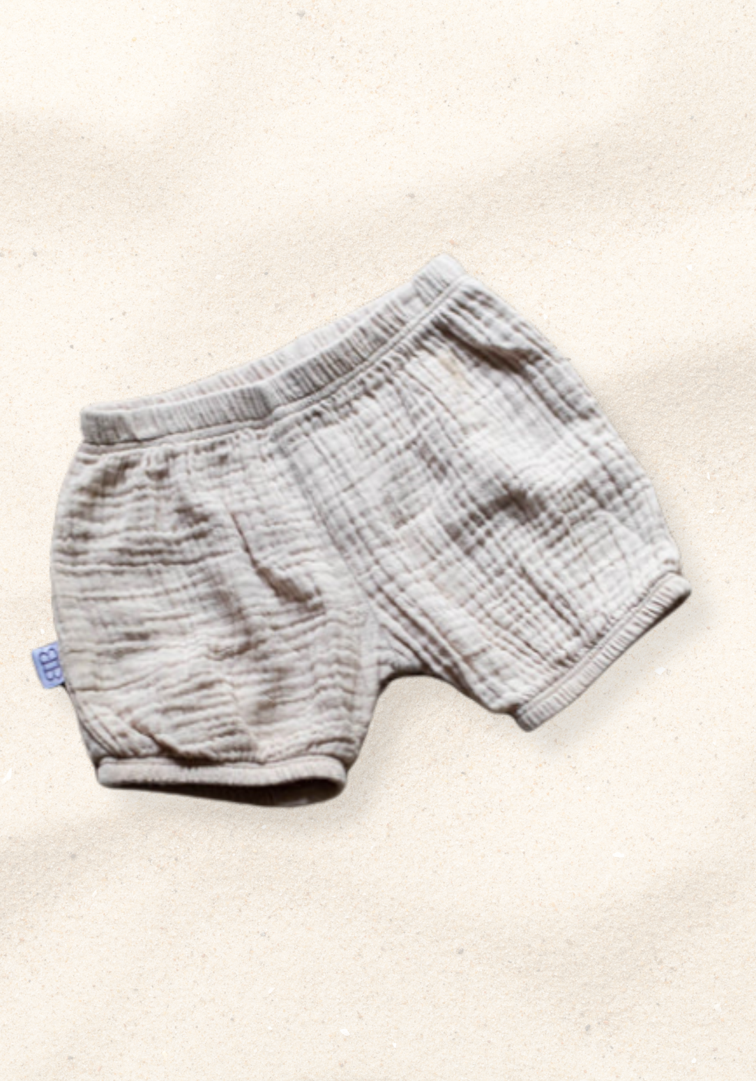 Three-pack of organic cotton baby bloomers in assorted neutral tones with elastic waist and leg openings