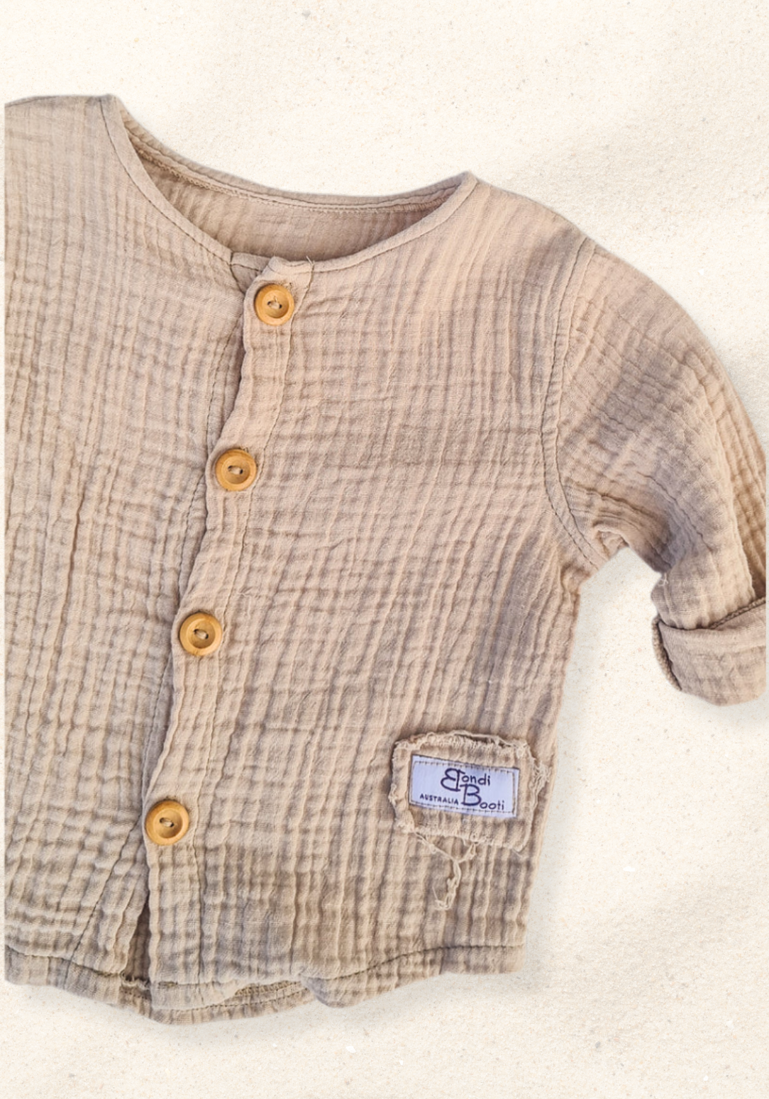 Beige organic cotton island-style shirt for babies and toddlers, featuring front wooden buttons and rolled sleeves