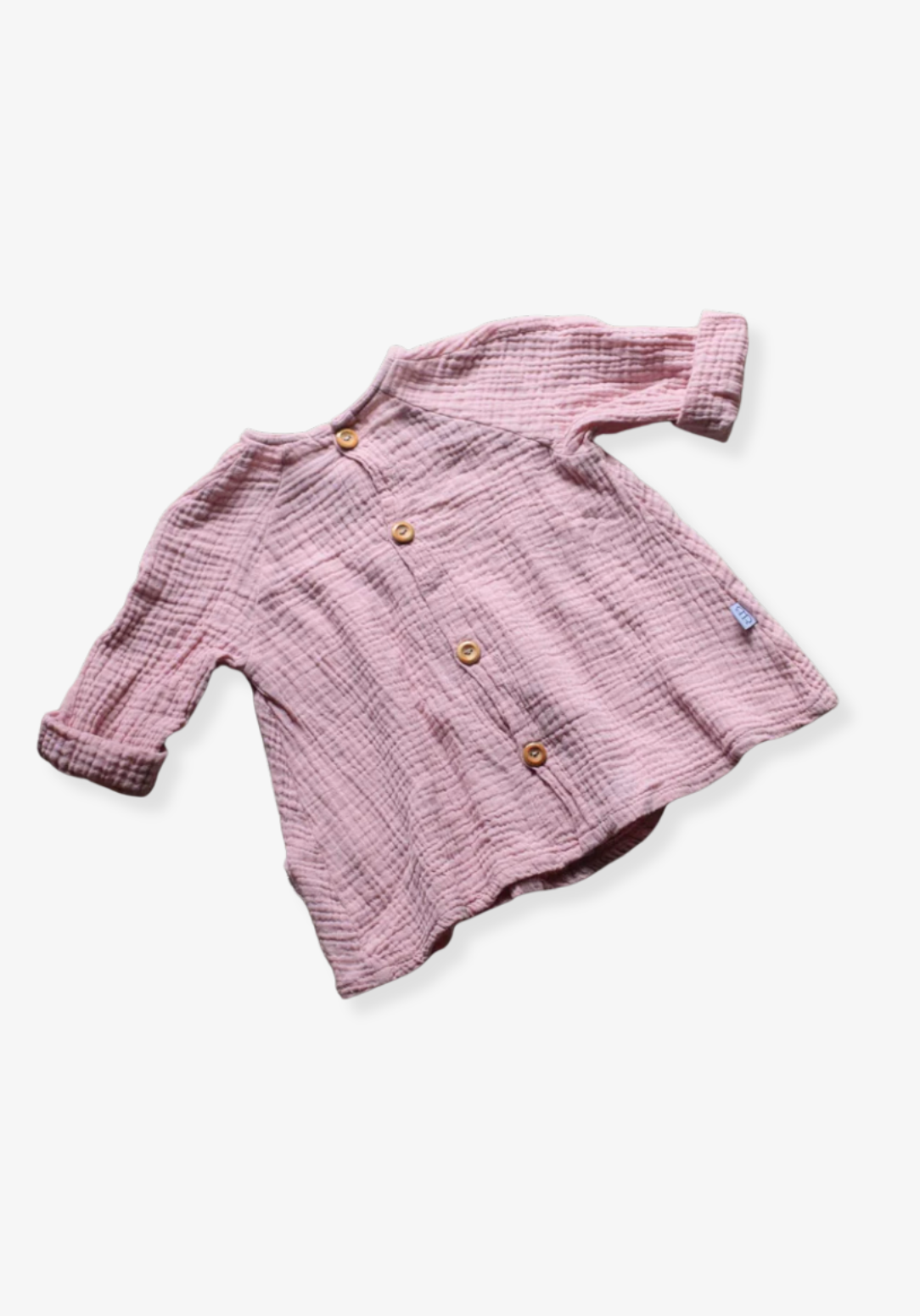Front view of dusty pink boho muslin long sleeve baby dress with wooden buttons and soft gauze texture on grey background