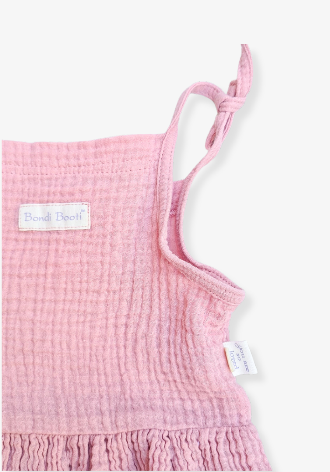 Dusty pink cotton baby dress styled for picnics, with flutter sleeves and soft gathered fabric, displayed on a grey background.