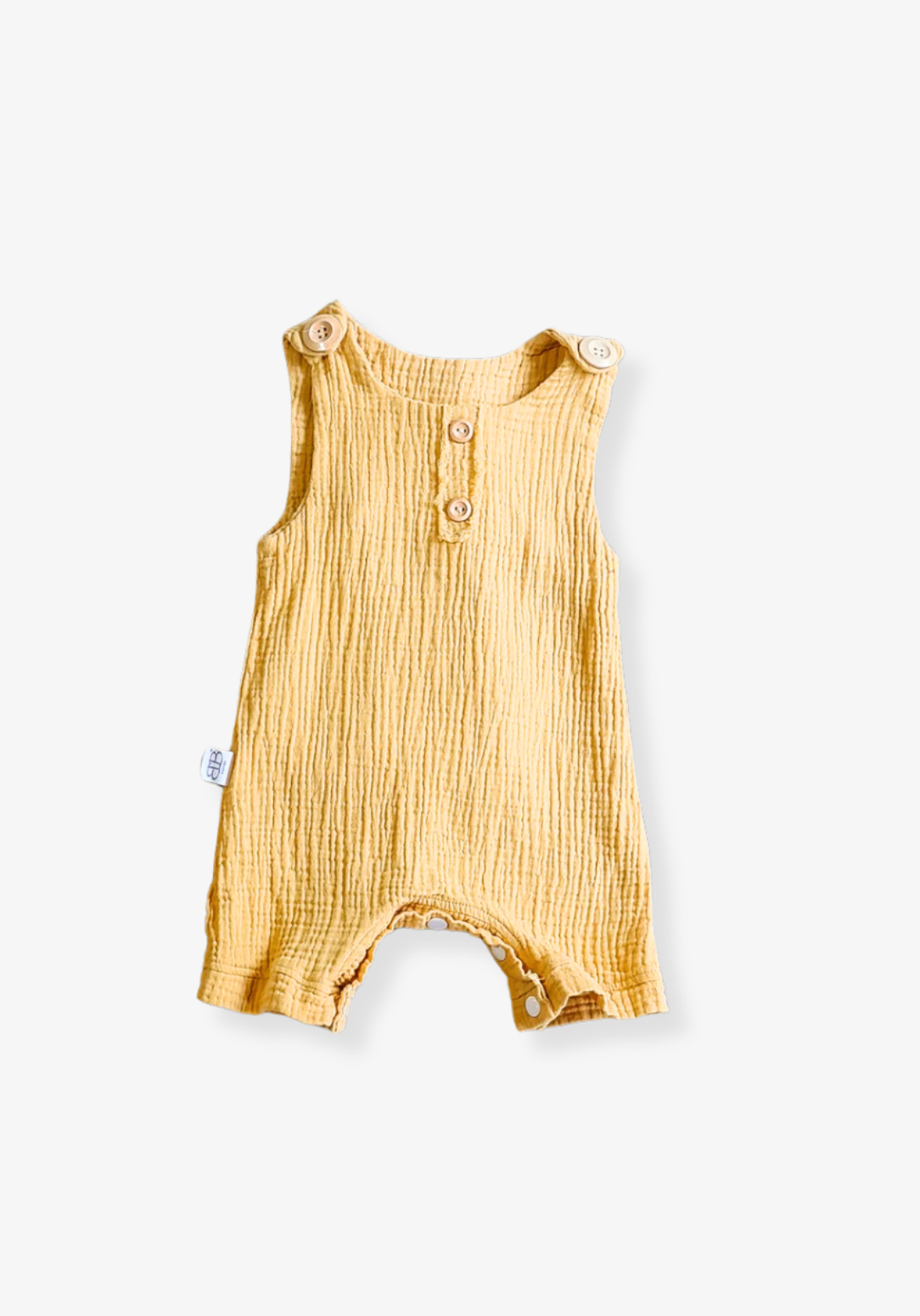 Mustard-colored organic cotton baby overall onesie with easy-change snaps on the bottom and wooden buttons on the shoulders.