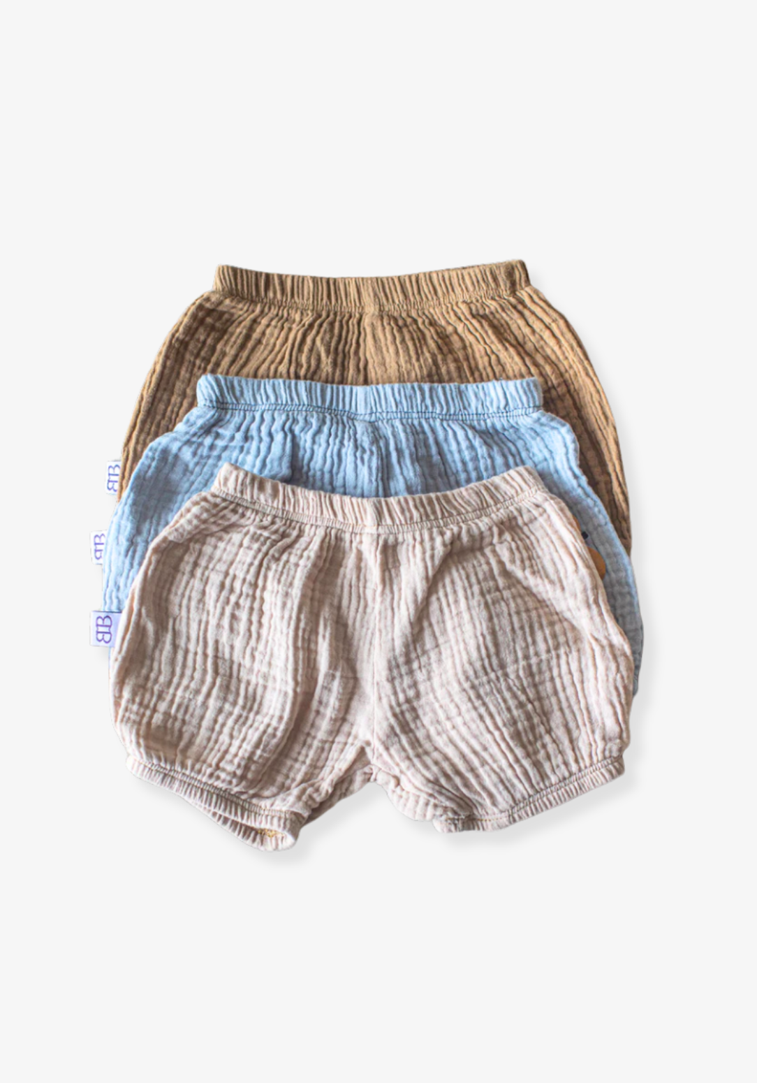 Three-pack of organic cotton baby bloomers in assorted neutral tones with elastic waist and leg openings