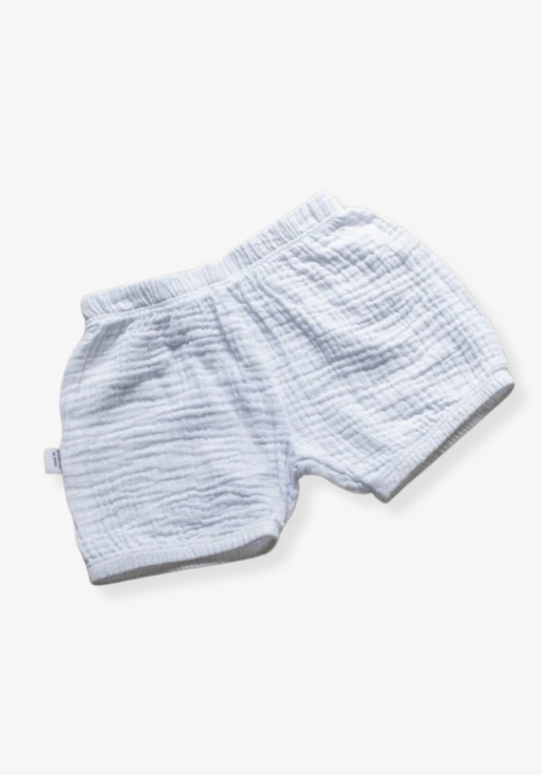 Minimalist white baby bloomers made from breathable organic cotton, displayed on a grey background with elastic details