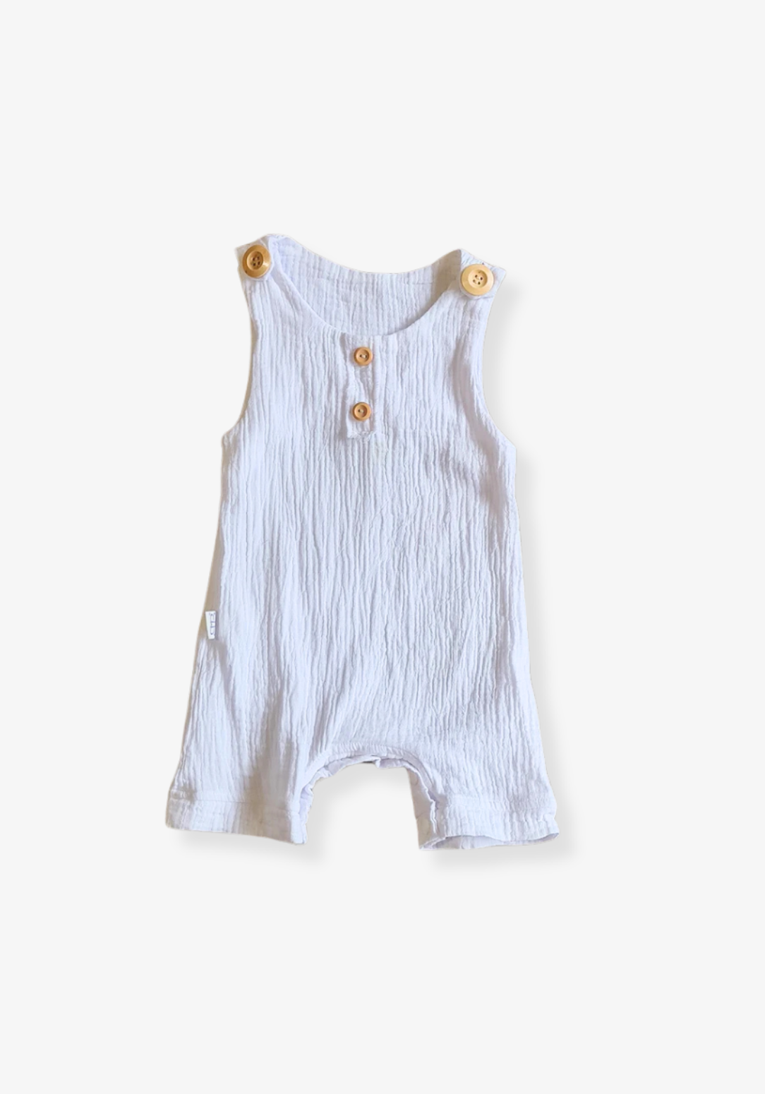 White baby overall onesie made from breathable organic cotton with wooden buttons and crotch snaps.
